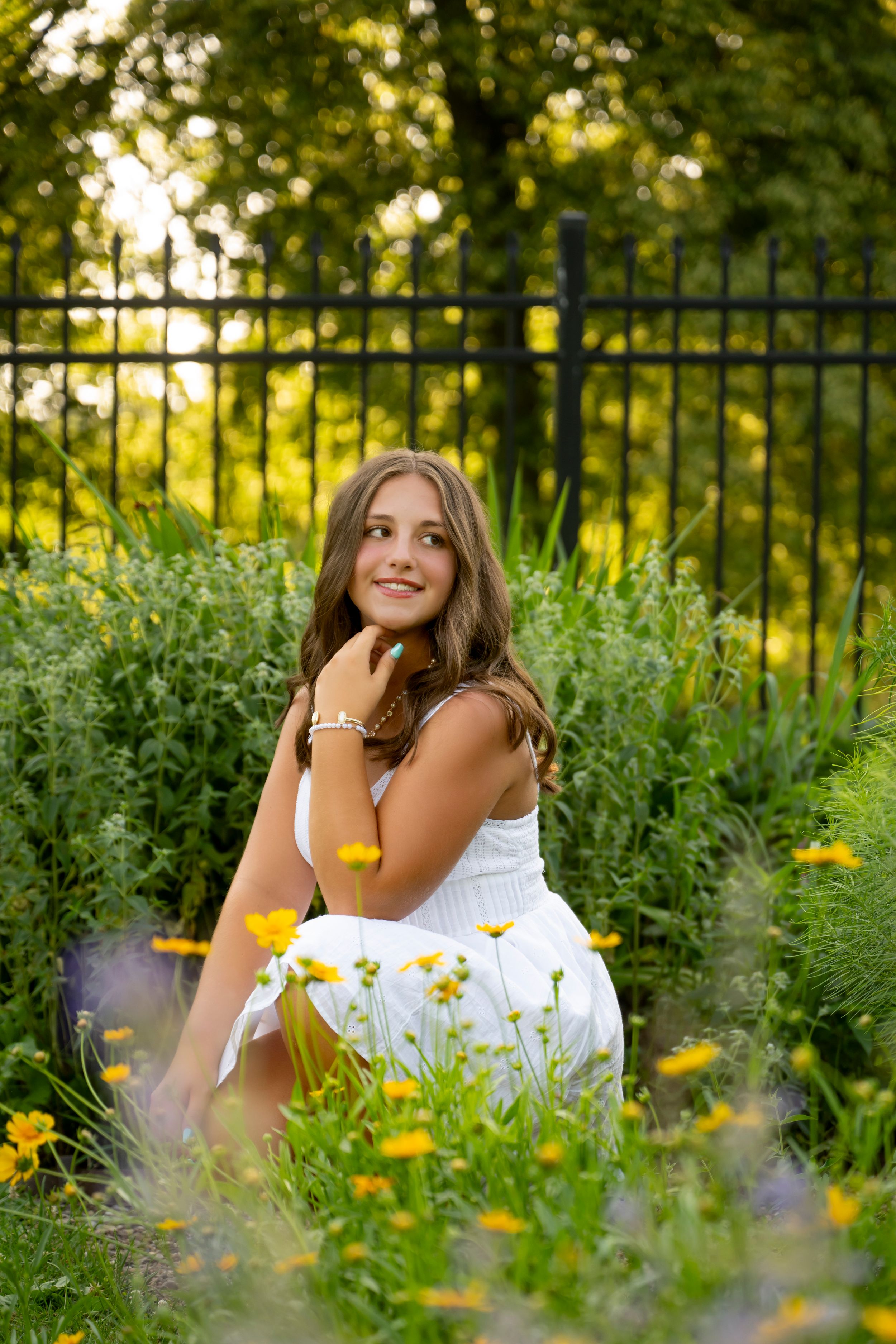 A white dress contrasts beautifully against lush greenery and yellow wildflowers in an outdoor garden setting.