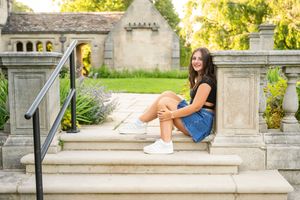 Person in casual summer outfit lounging on stone steps in a scenic garden setting with golden sunlight.