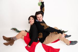 Artistic photo shoot with green garland and red fabric against white background.