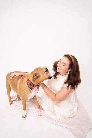 Tan dog and person in white dress interacting playfully during photo session.