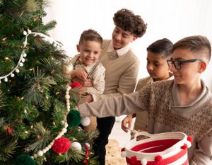 Group decorating Christmas tree with ornaments and garland in cozy holiday setting.