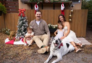 A group relaxes outdoors with their white and brown spotted dog on a sunny afternoon.