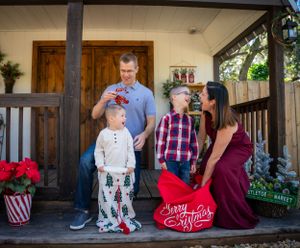A family shares a candid moment on a porch decorated with poinsettias for the holidays.