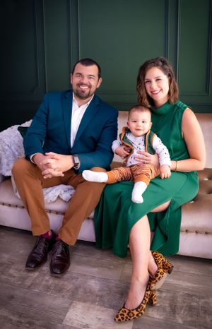 Family poses on modern couch during professional indoor photo session.