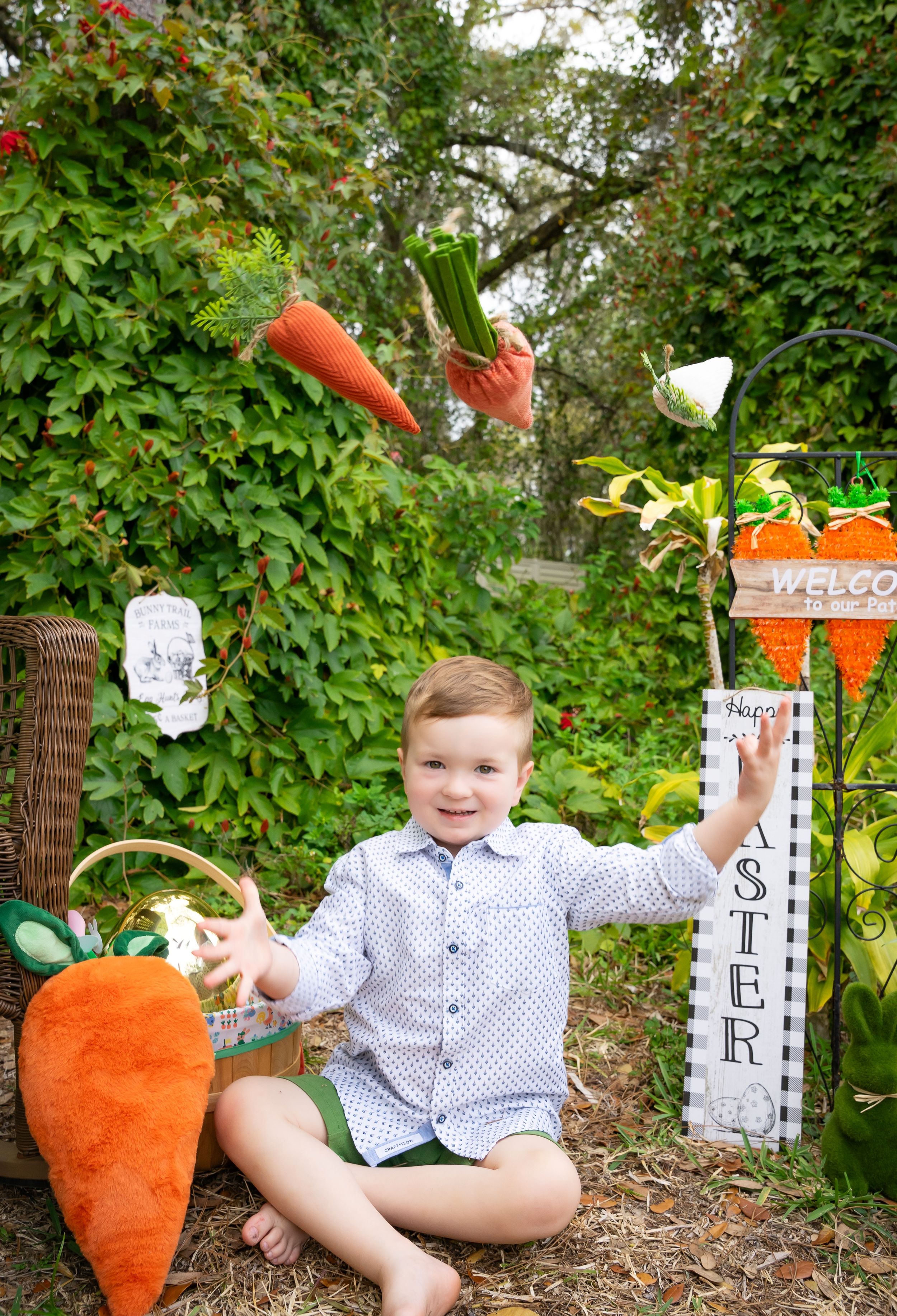 A garden setting with decorative white fences and large orange carrot props.