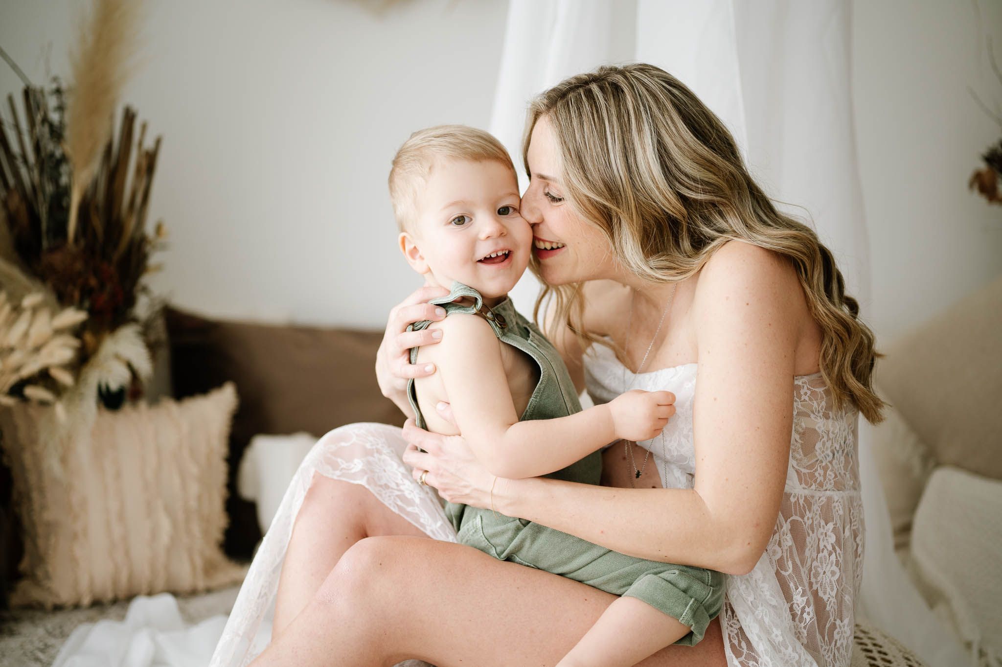 Sweet maternal moment captured in soft natural light with neutral decor.