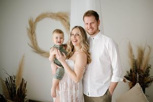 Family portrait with baby in front of decorative pampas grass wreath and dried flowers.