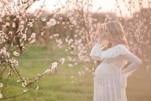 A dreamy maternity portrait captured among spring blossoms during sunset.