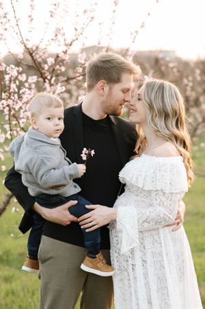 A loving family moment captured in a blooming spring orchard at sunset.
