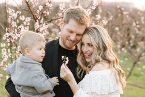 A family shares a tender moment among blooming cherry trees during a spring photoshoot.