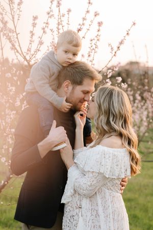 An intimate family portrait captured among blooming spring trees at sunset.