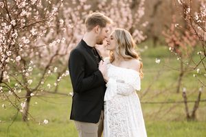 A romantic couple shares an intimate moment among blooming spring trees.
