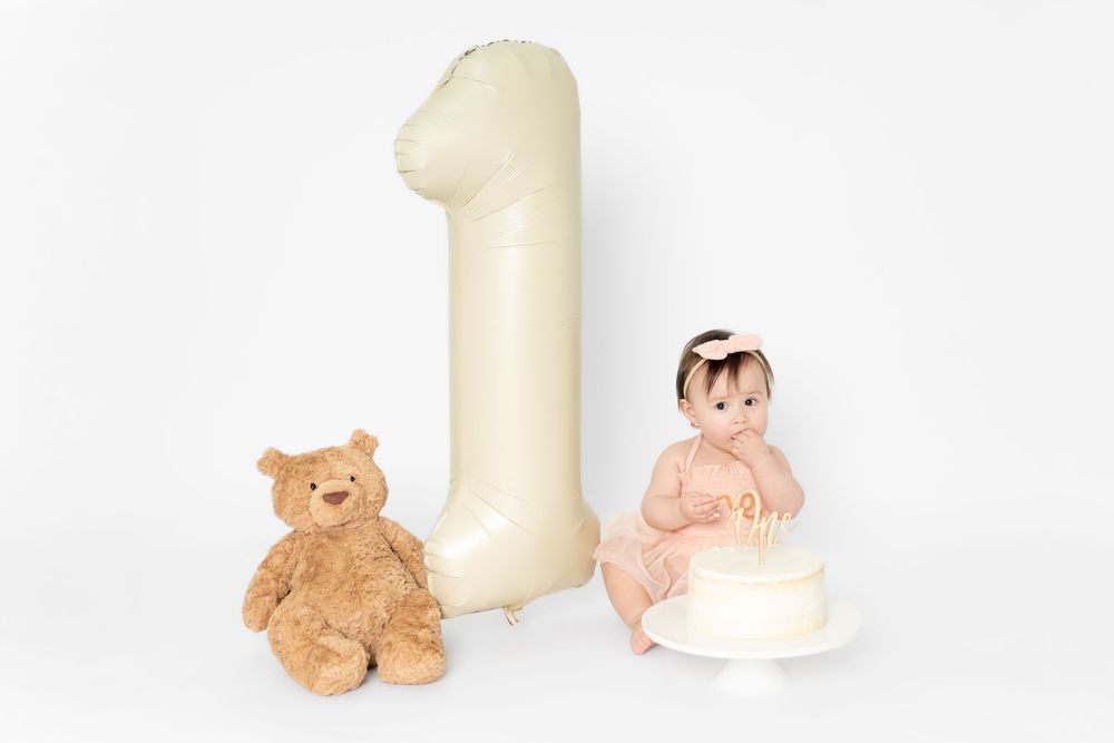 A row of plush teddy bears and stuffed animals arranged next to tall white candles on a white surface.