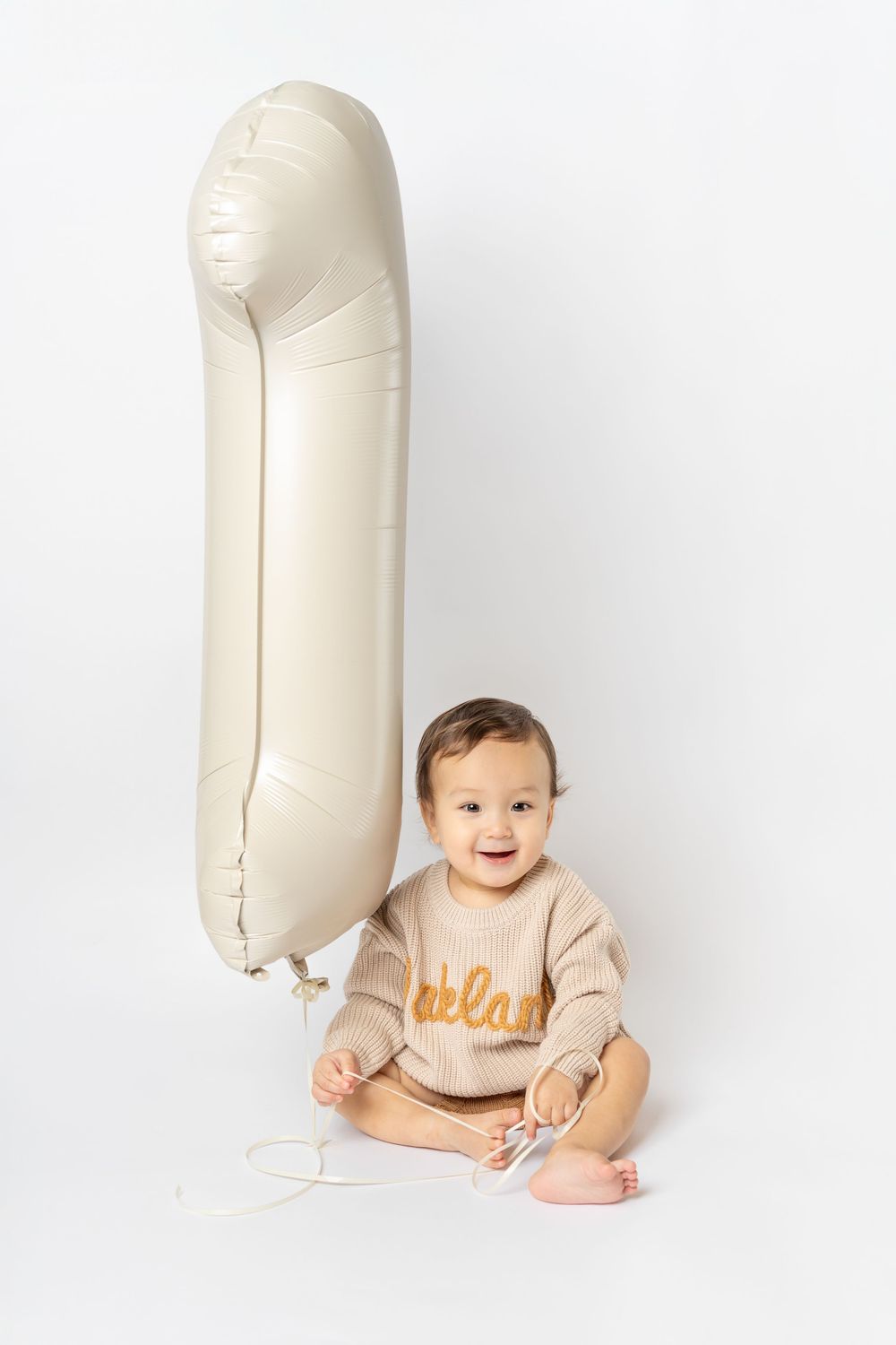 Three sequential photos show a baby sitting next to large white inflatable numbers against a white background.