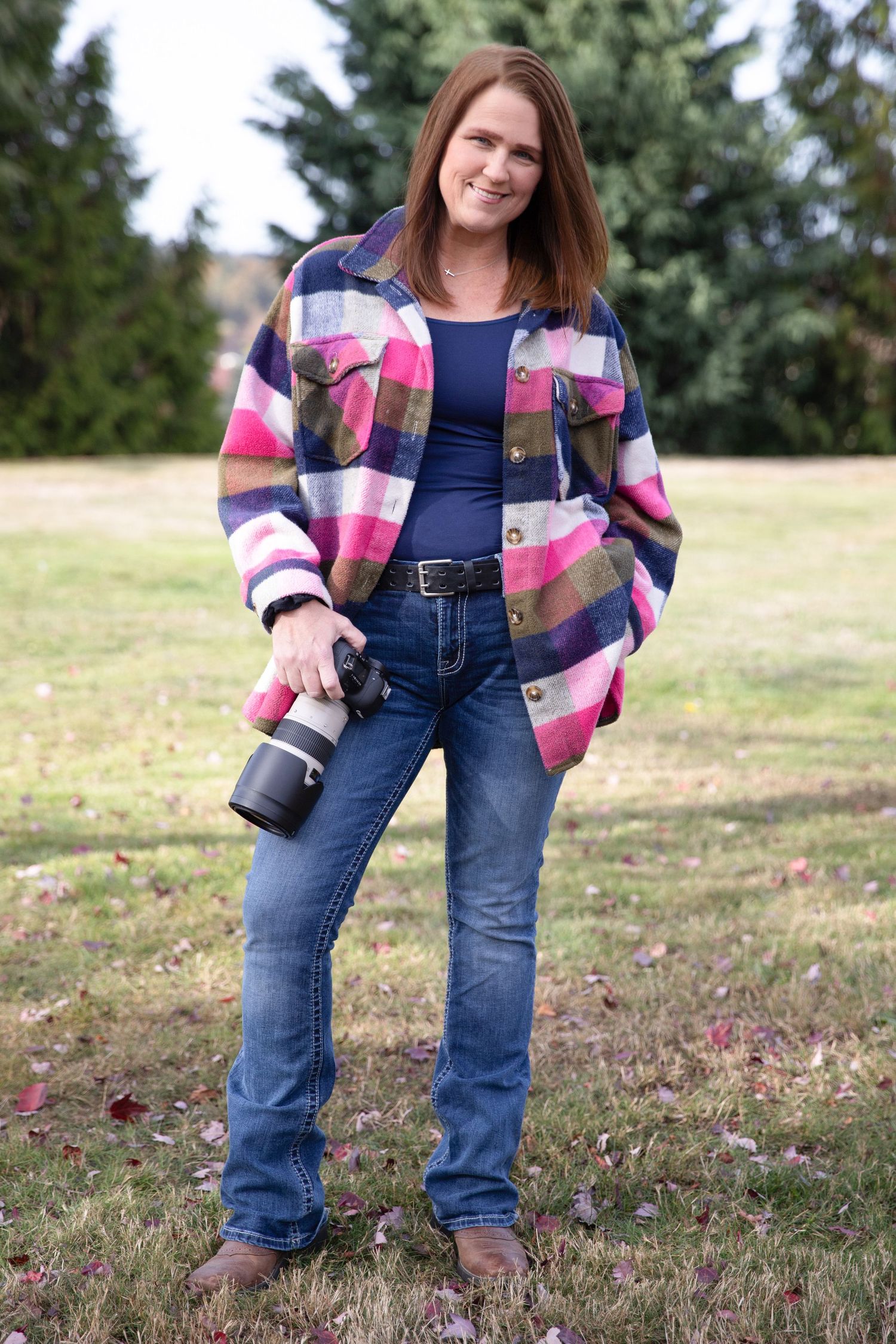 Portrait of photographer sitting on concrete steps wearing black top and striped skirt.