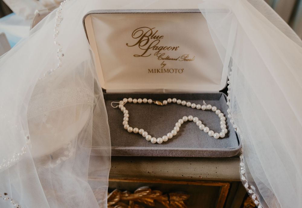 Mikimoto pearl necklace displayed in Blue Lagoon jewelry box draped with white bridal veil.