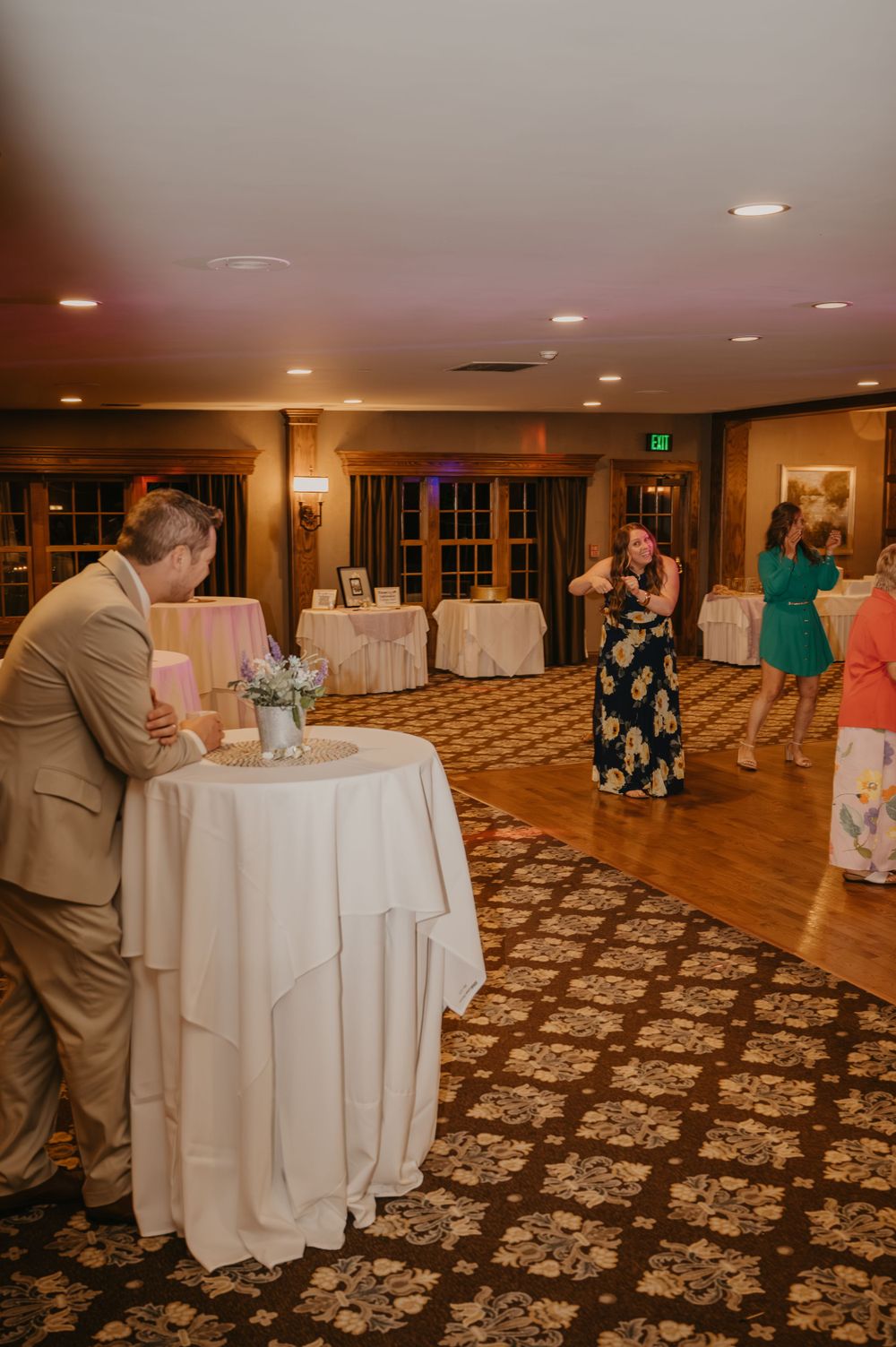 Wedding reception guests dancing and socializing in warmly lit ballroom venue.
