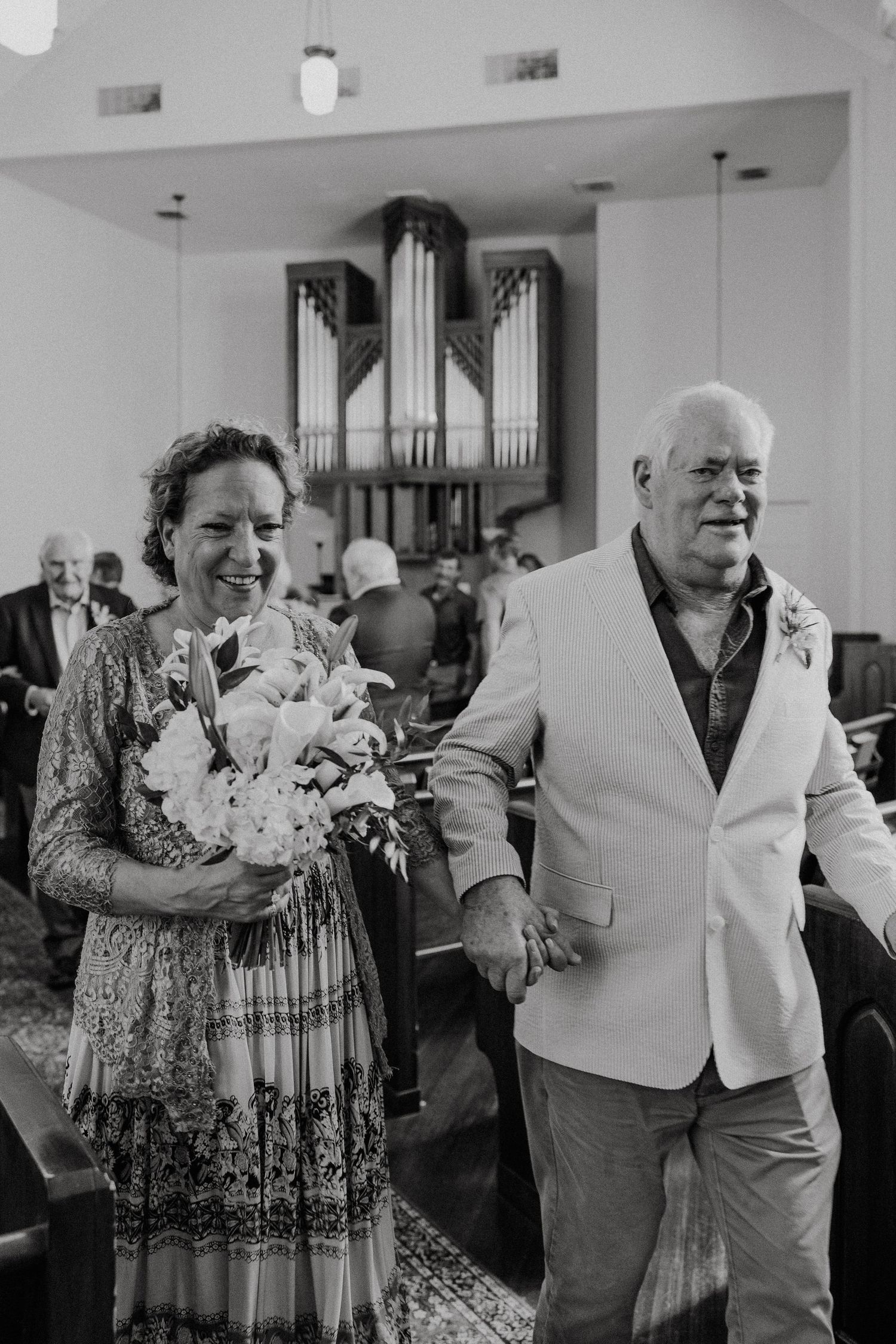 Black and white photo of people holding bouquets during a church celebration.