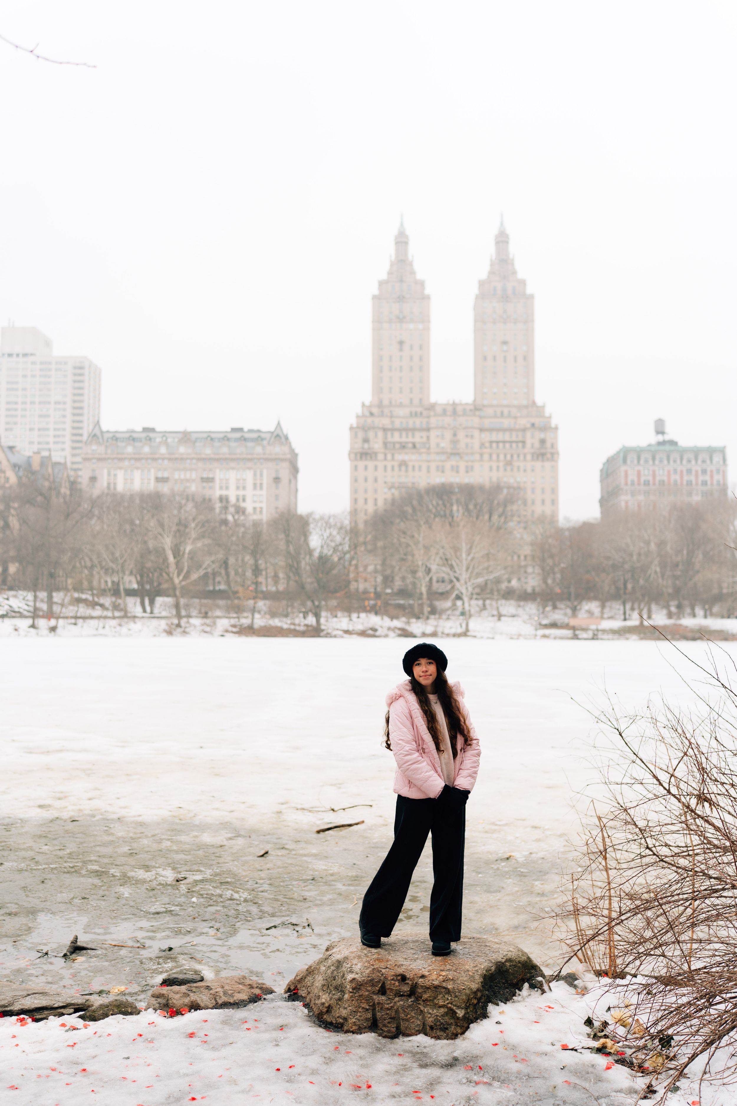 Winter scene in Central Park with snow covered landscape and iconic San Remo towers in background, New York City.