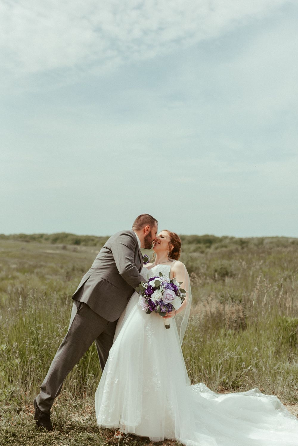 Couple sharing a romantic moment in a field during their wedding photo session.