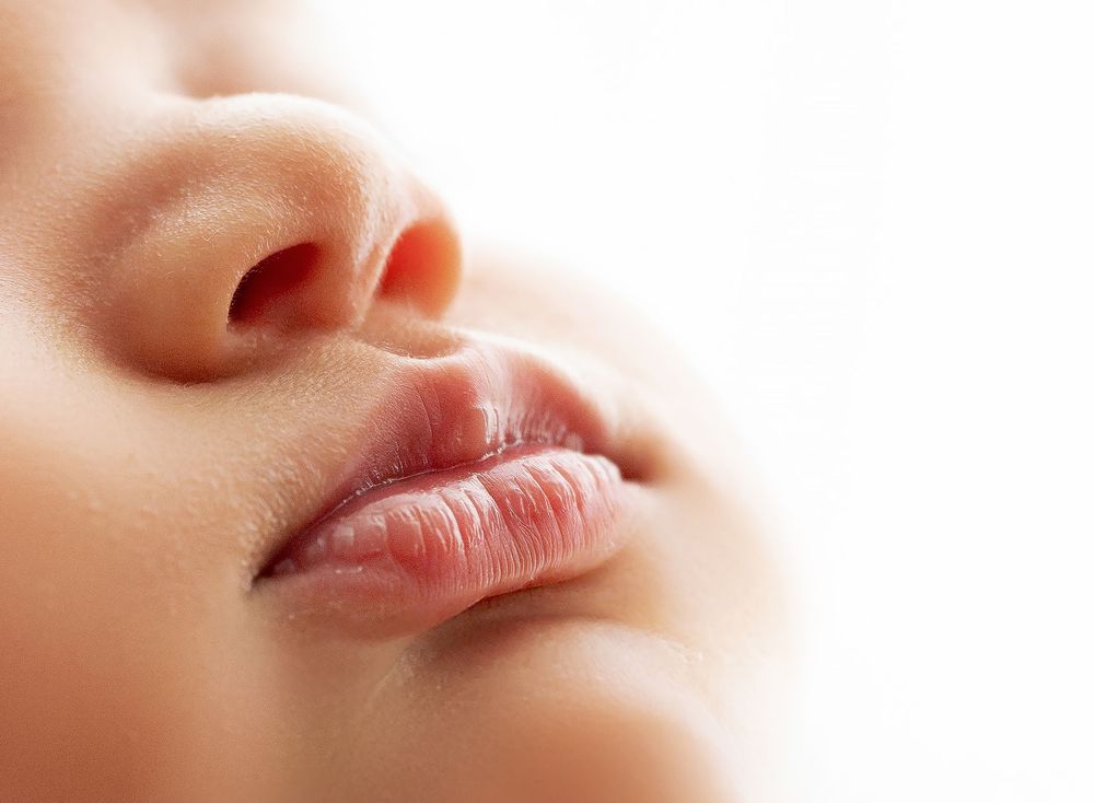 Close-up macro shots of soft pink lips arranged in a horizontal row against a beige background.