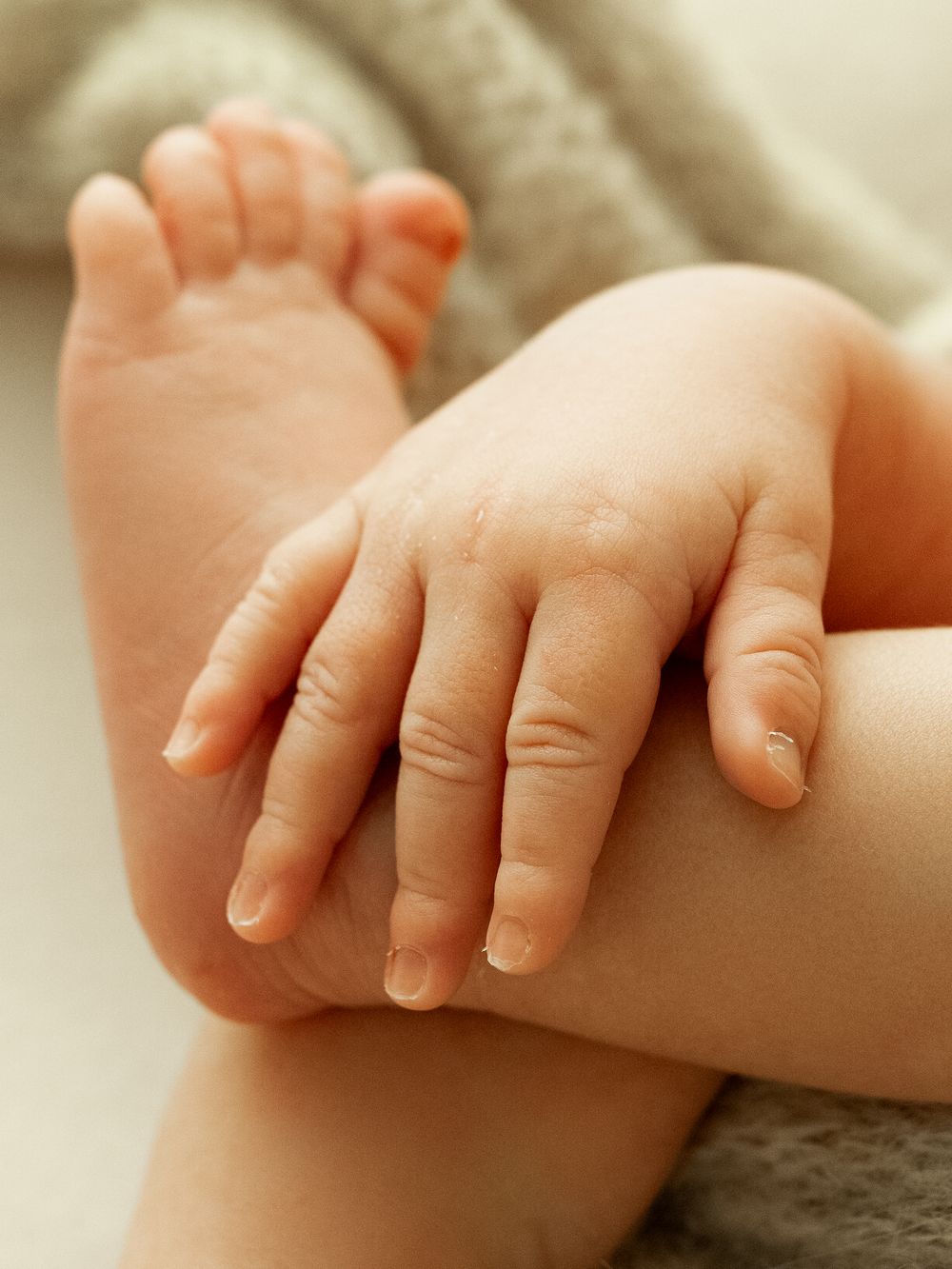 Close-up sequence showing tiny baby fingers and hands against a light beige background.