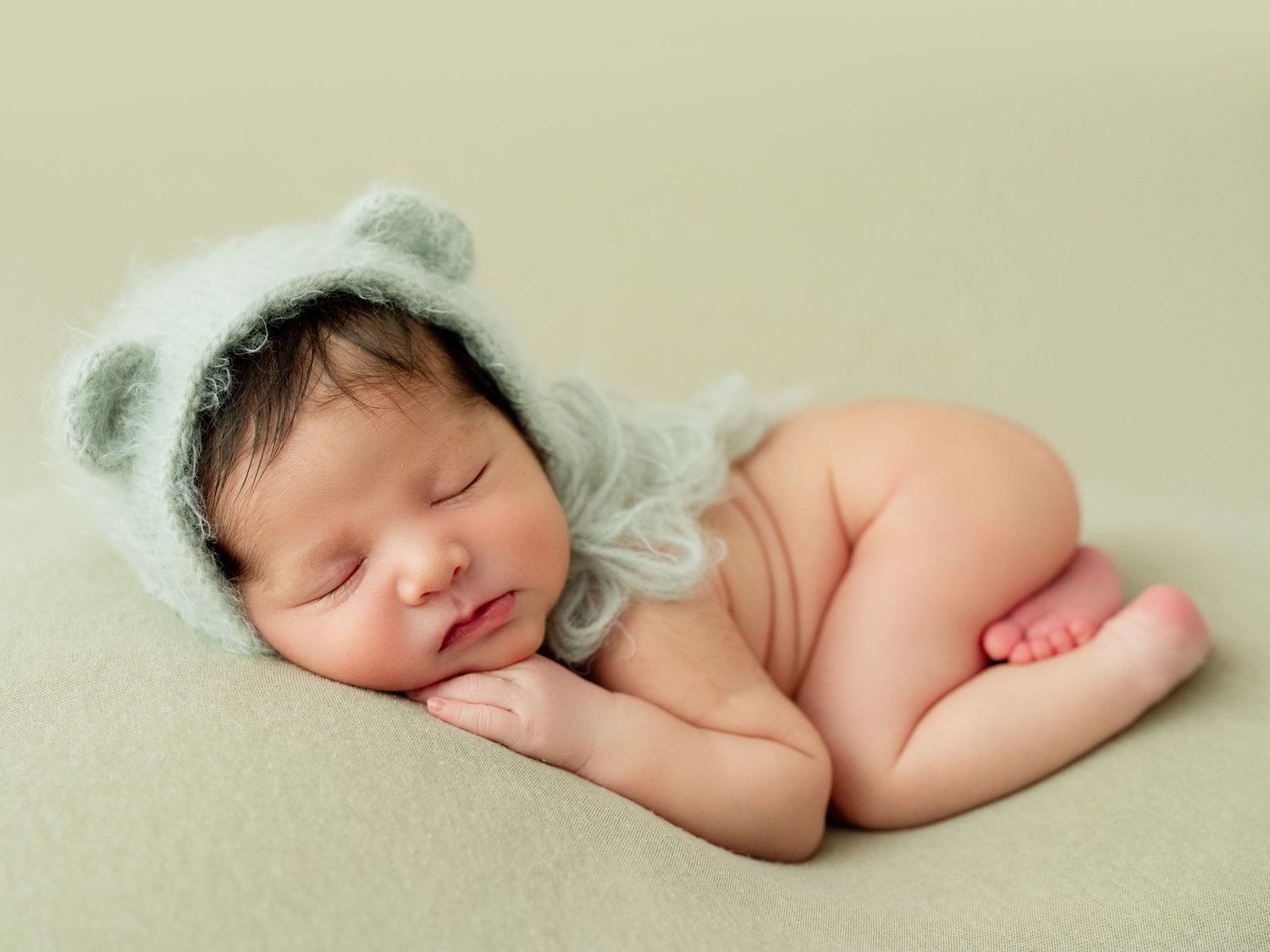 A sleeping newborn baby wearing a delicate white lace outfit.