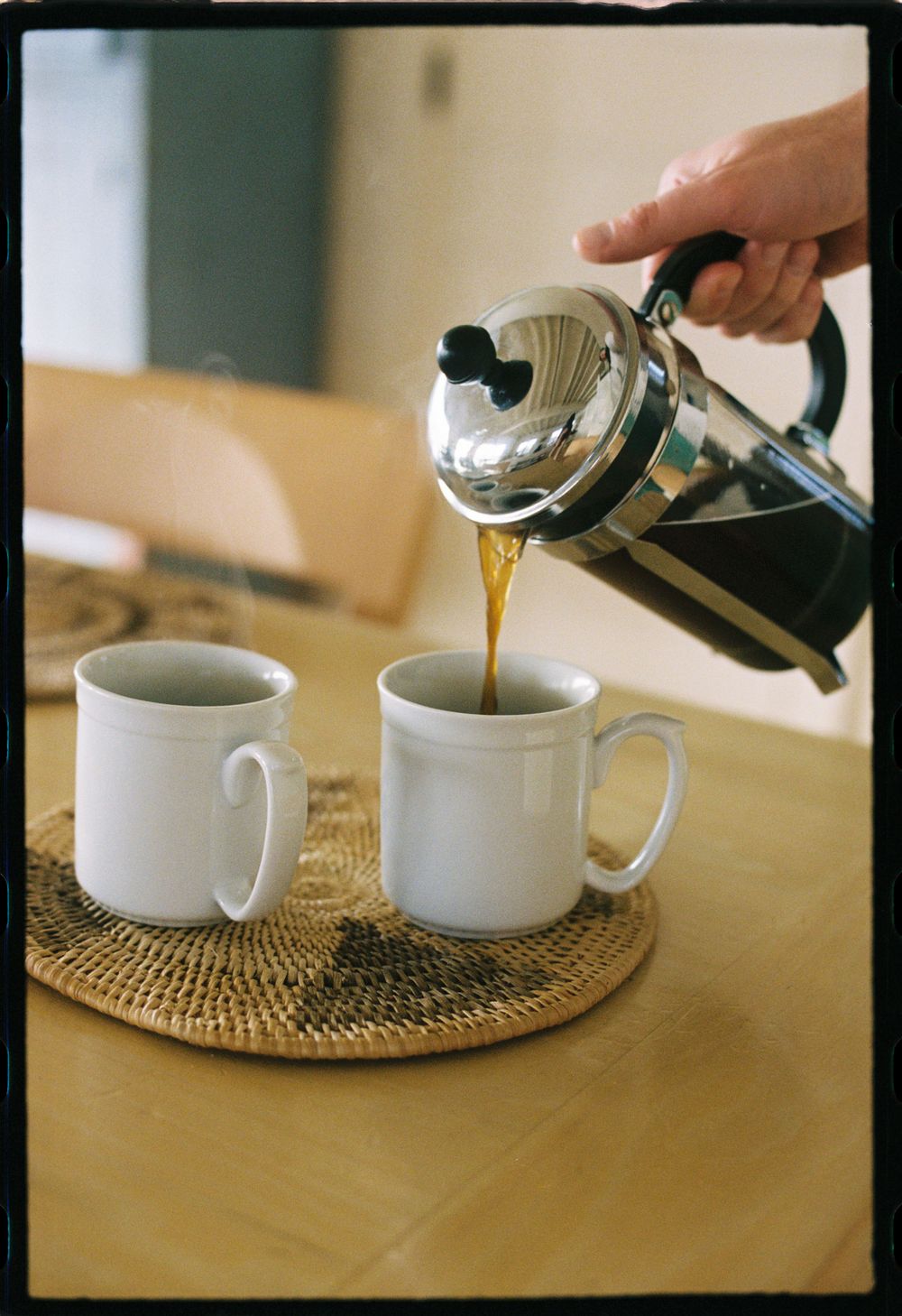 Detail of someone pouring coffee from a french press at the table.