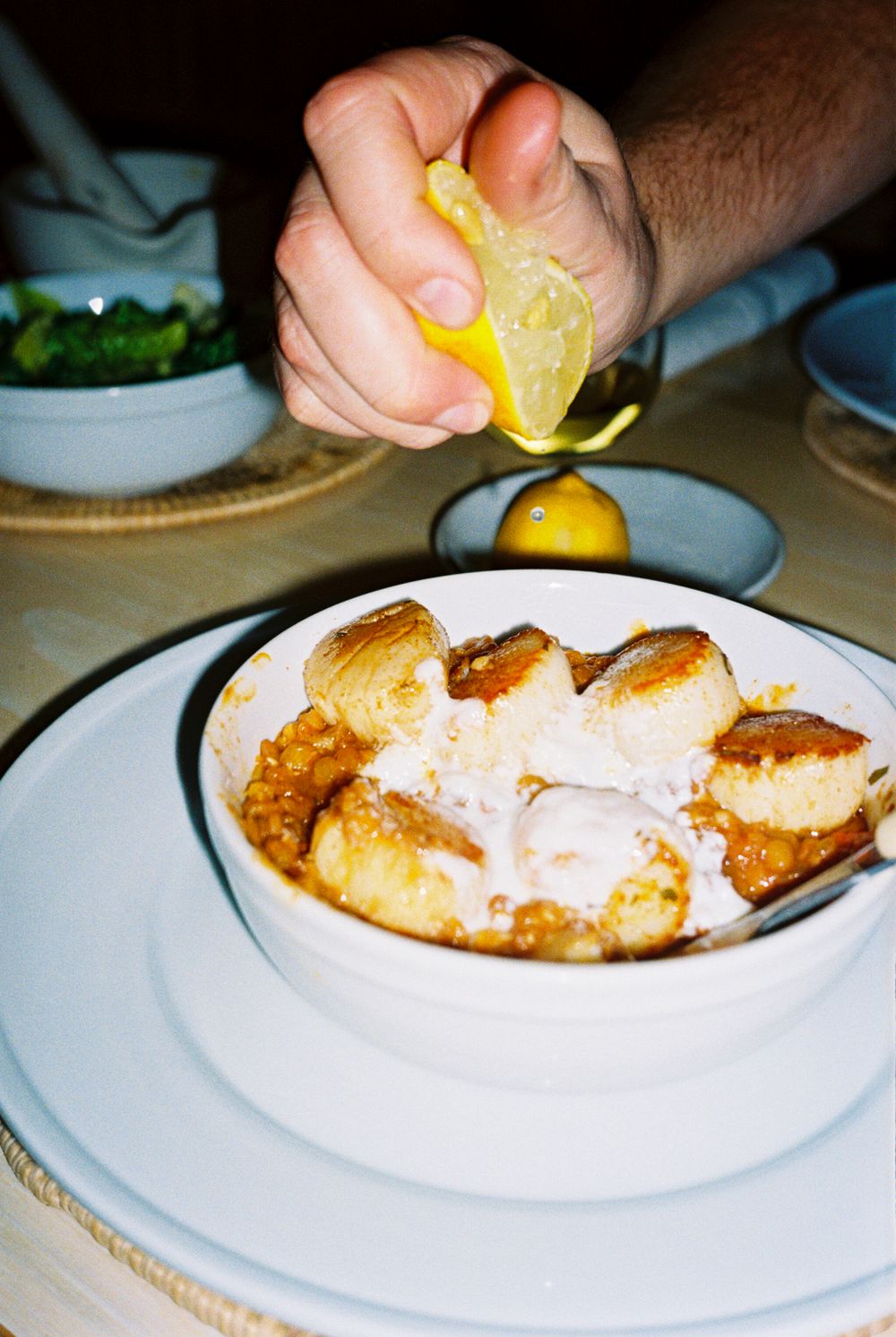 Detail of lemon being squeezed onto a dish of seared Maine scallops at Harbor Cottage in Rockland, Maine.