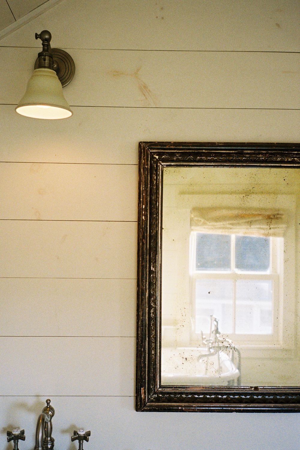 Detail of vintage mirror reflecting claw foot bathtub at Harbor Cottage in Port Clyde, Maine.