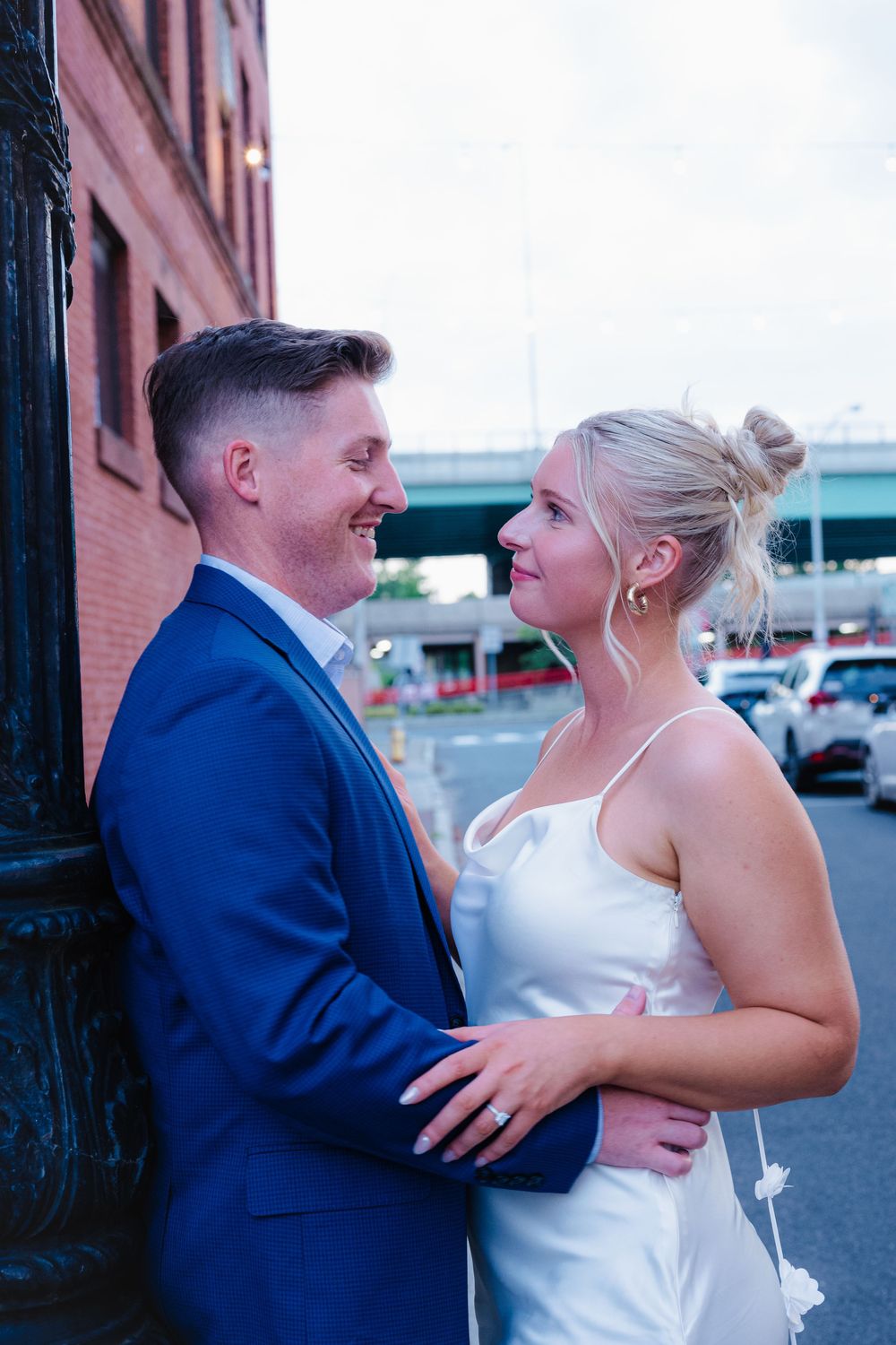 Romantic couple in wedding attire sharing intimate moments against a brick building exterior.