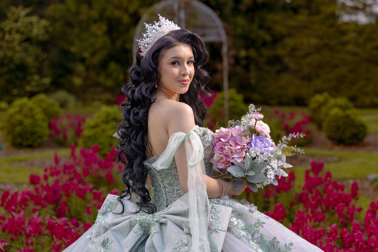 Ethereal portrait in mint green gown among vibrant spring flowers.
