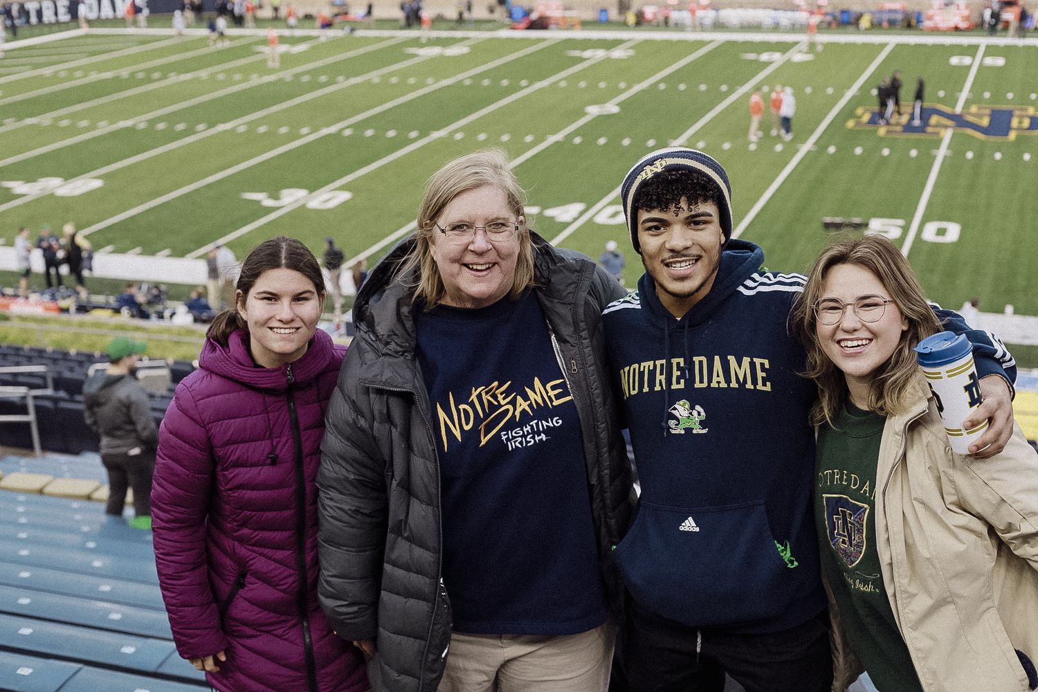 Friends enjoying a football game together in the stadium stands on a sunny day.