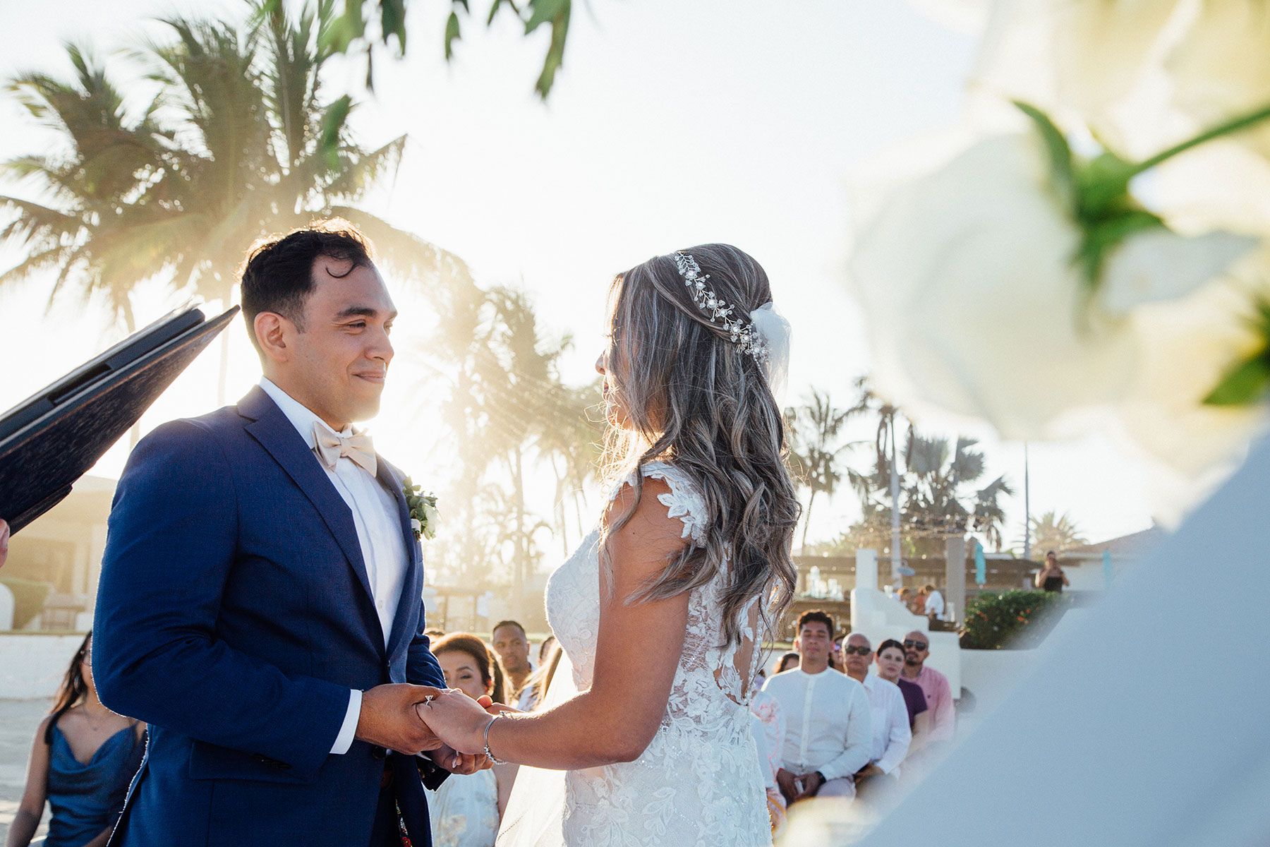 Bride and groom hold hands exchanging vows at outdoor beach wedding.