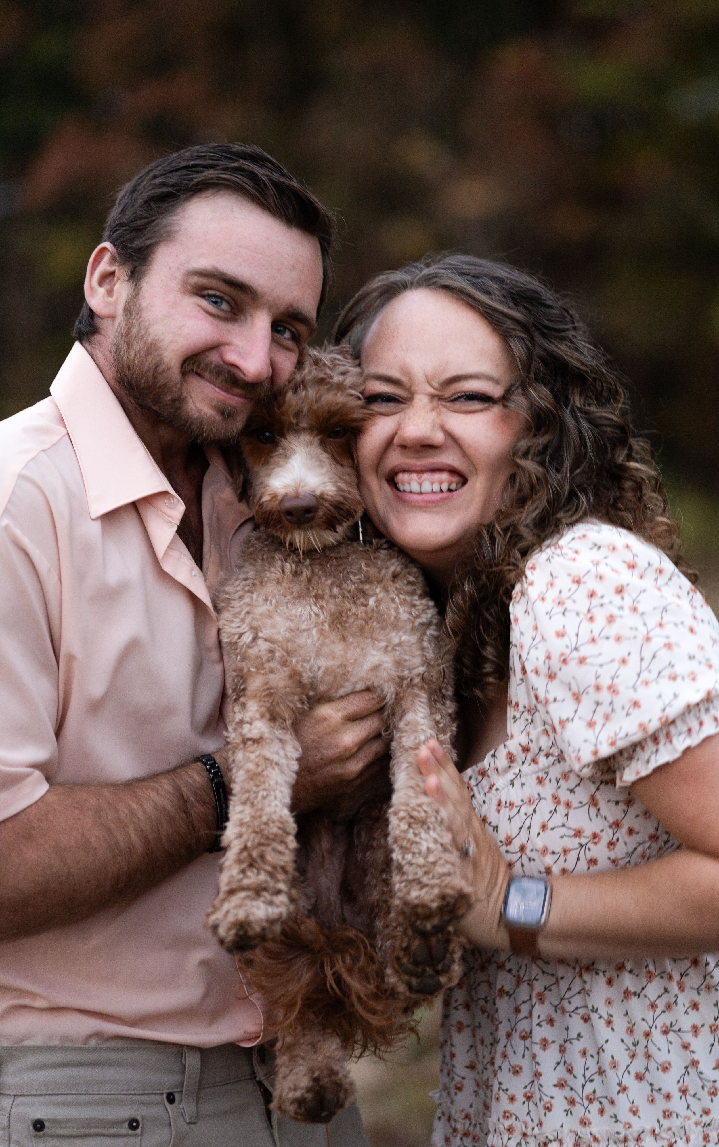 Happy couple poses with their fluffy brown dog for outdoor portraits.
