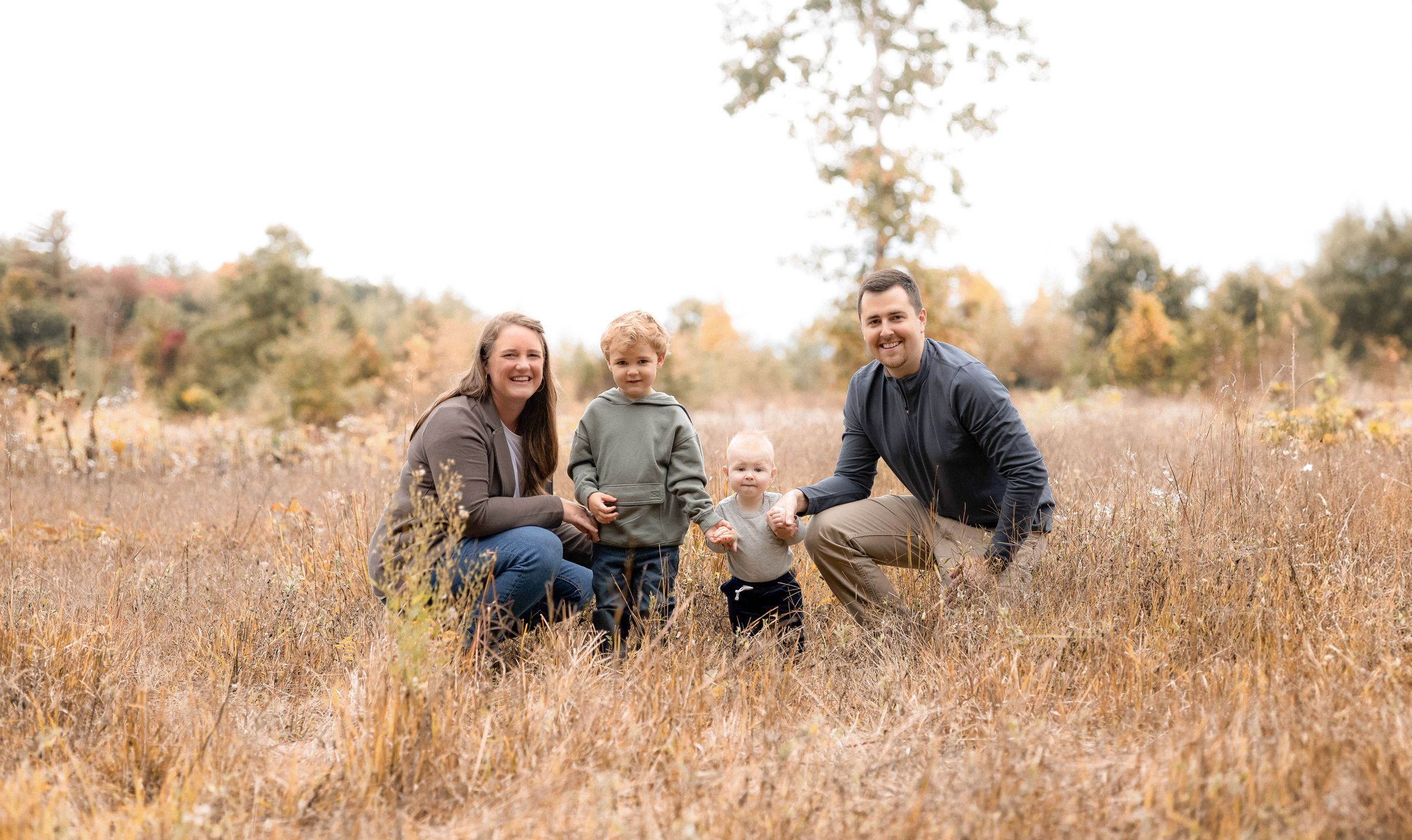 Distant view of family sitting together in autumn field at sunset.