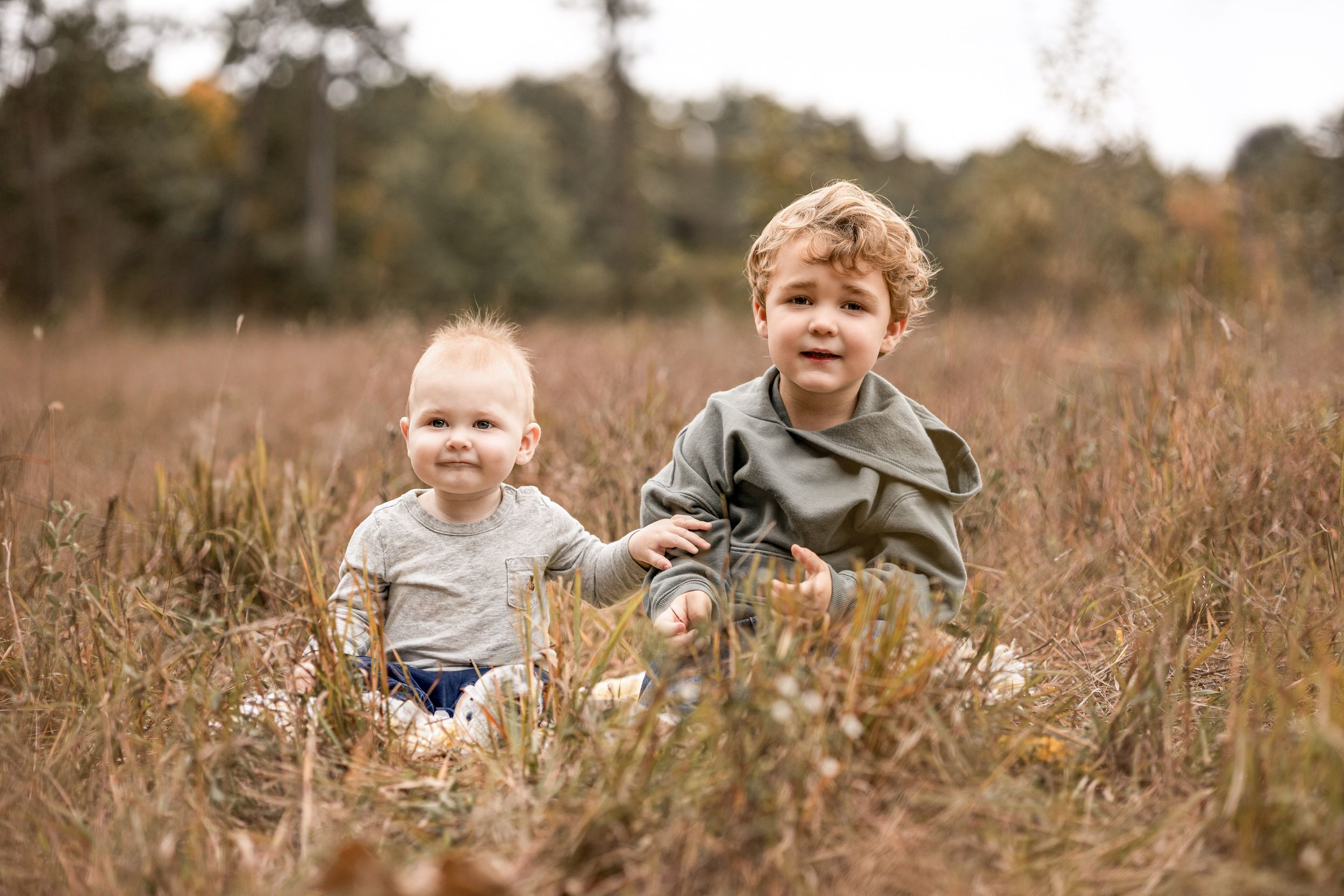 Children playing in tall grass field during golden hour.
