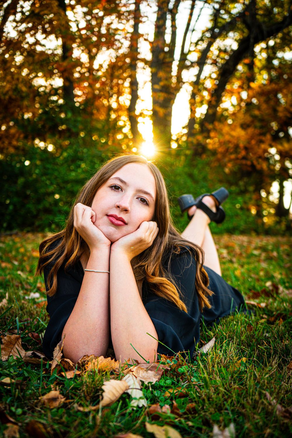 Autumn portrait in fallen leaves with golden sunlight filtering through trees.