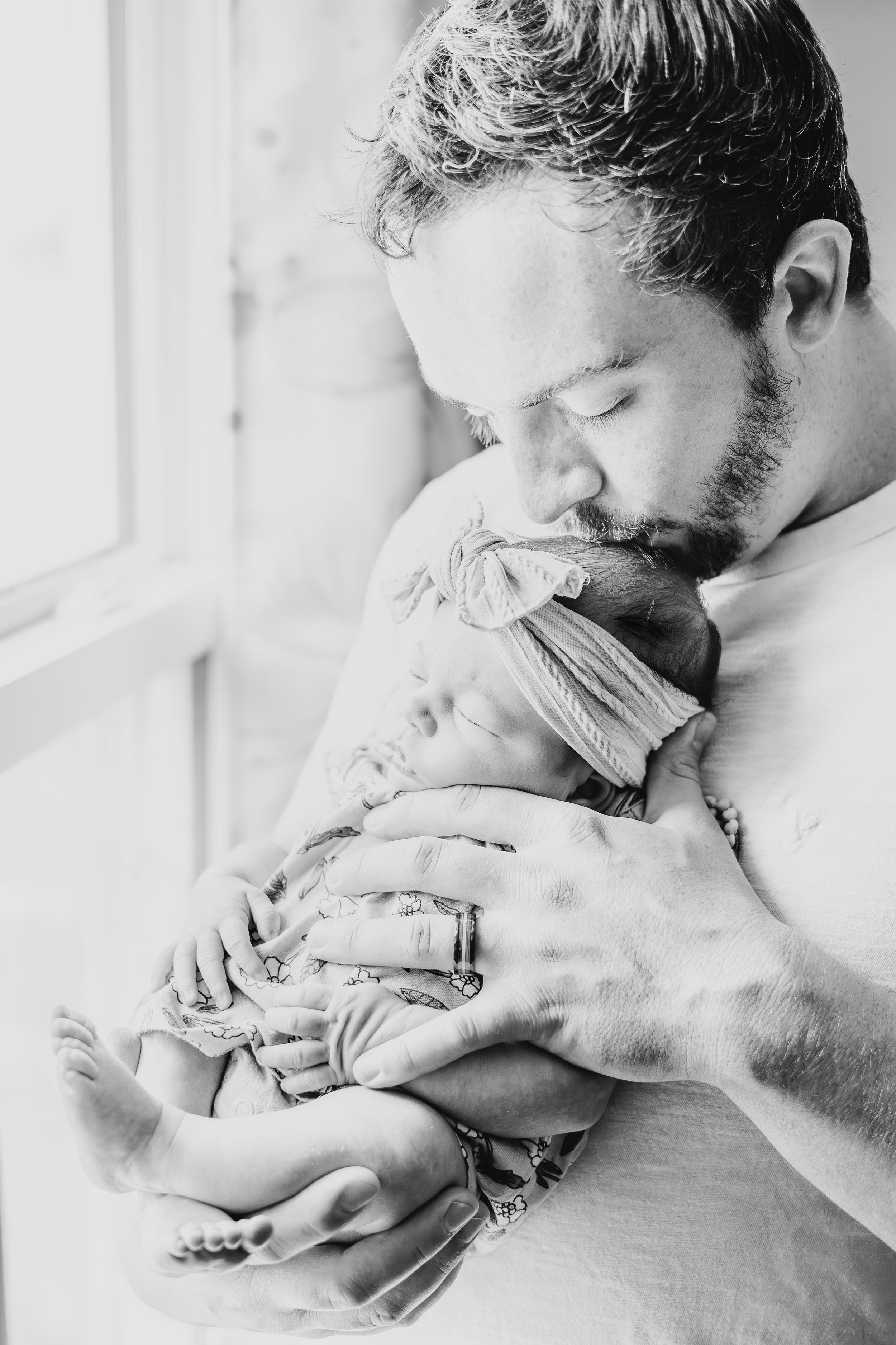 Black and white portrait of tender moment between parent and sleeping infant.