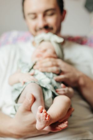 Close up of tiny baby feet while being held in white clothing.