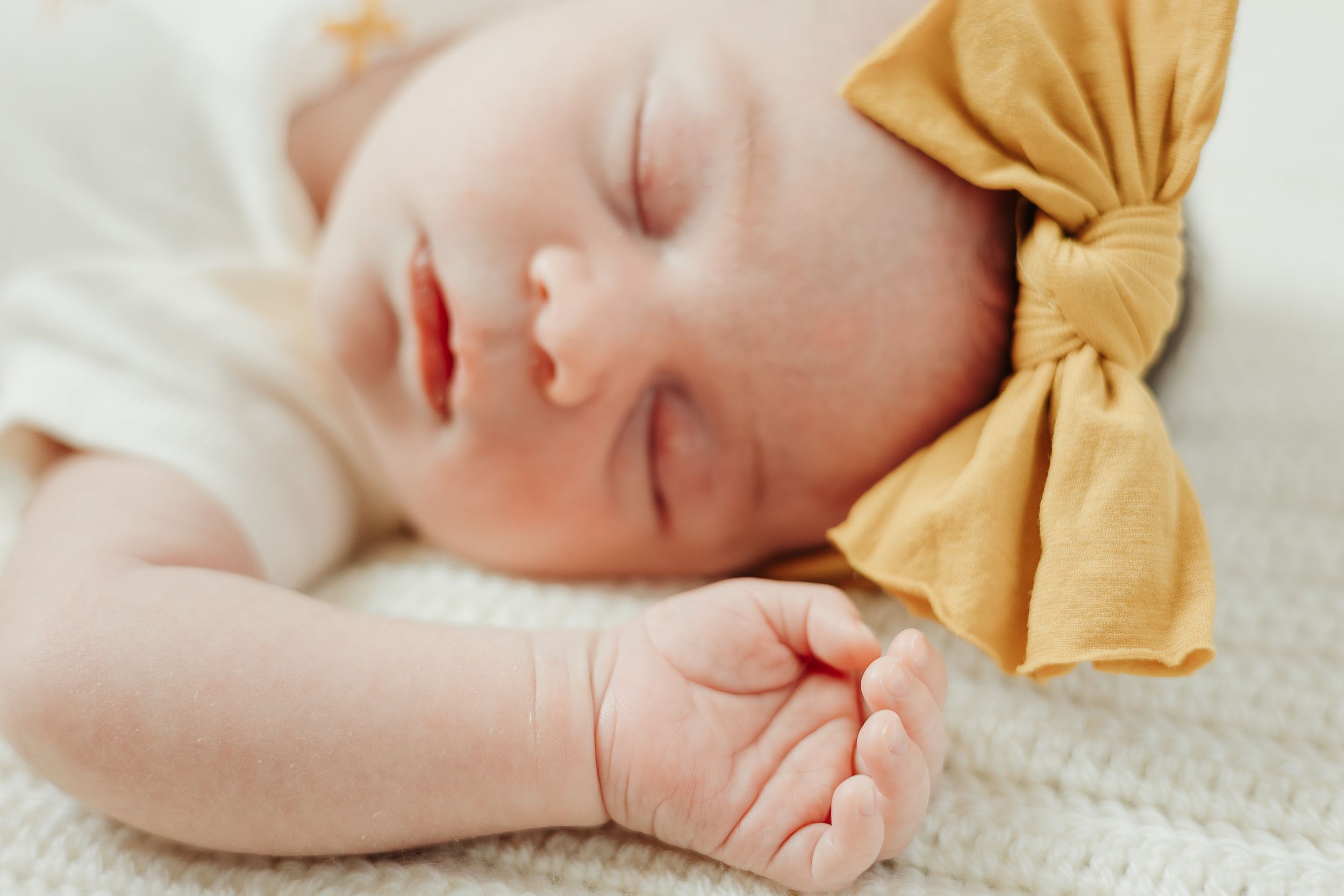 Peaceful sleeping baby wearing mustard yellow bow headband.