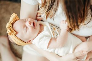Close-up of sleeping baby with yellow bow headband being cradled.