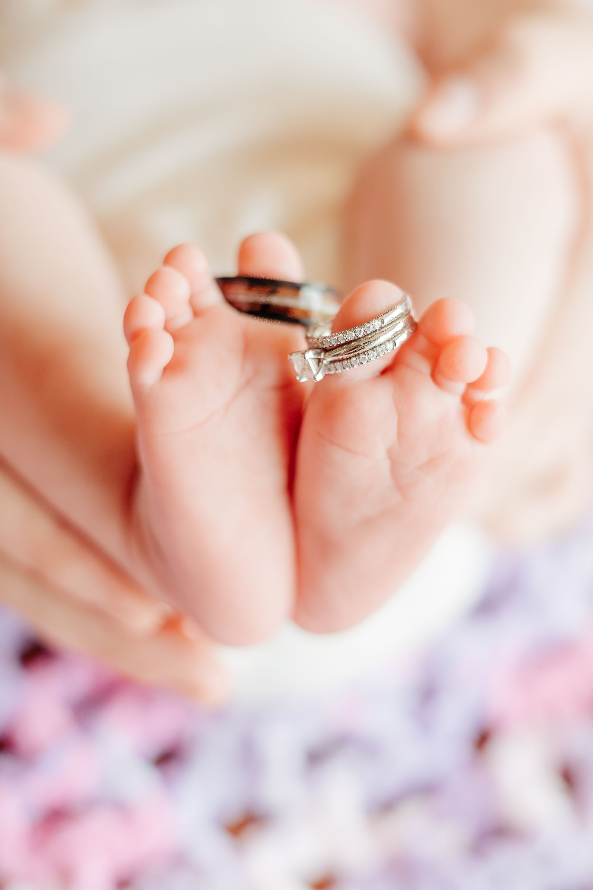 Wedding rings placed between tiny newborn baby feet.