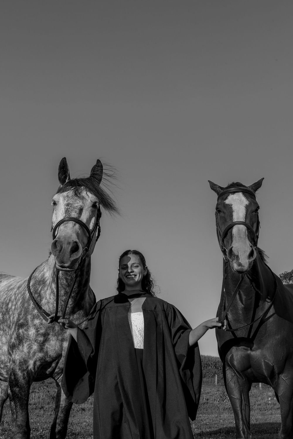Black and white photo of a girl in between two horses