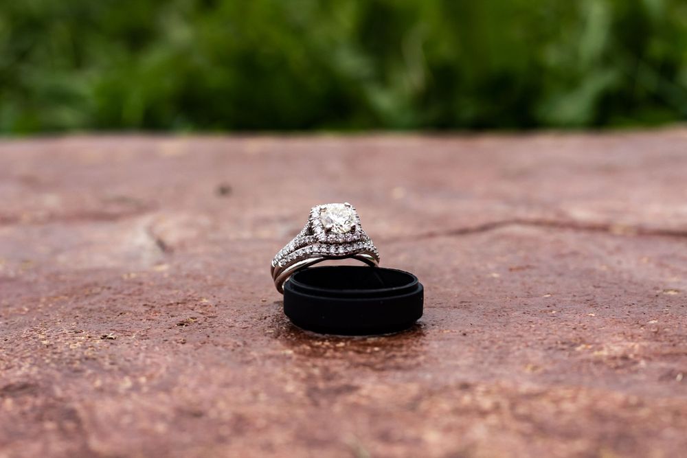 Elegant diamond wedding rings displayed on a rustic stone surface.