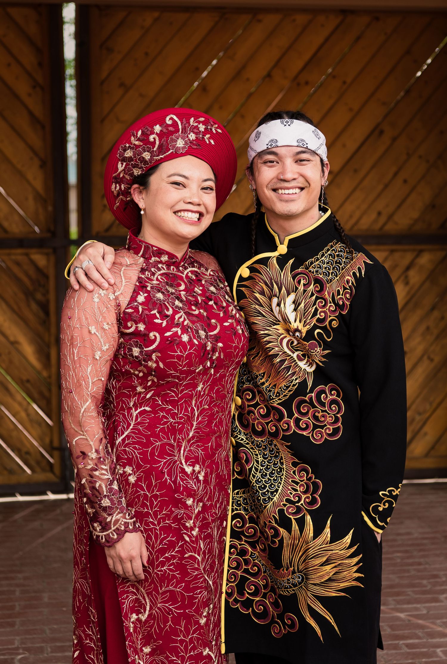 A couple in traditional Vietnamese wedding attire with intricate gold phoenix designs.