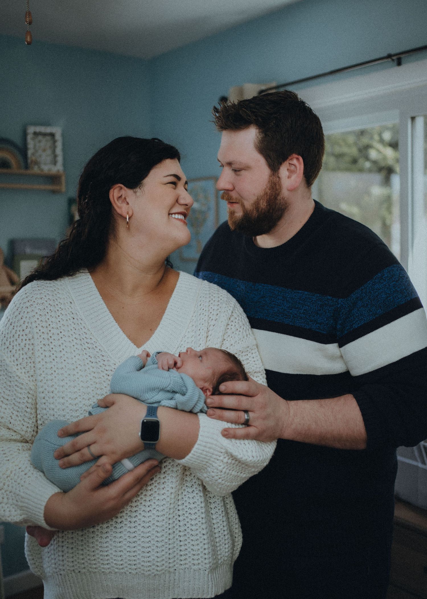 Loving parents sharing intimate moment while holding their newborn baby in cozy home setting.