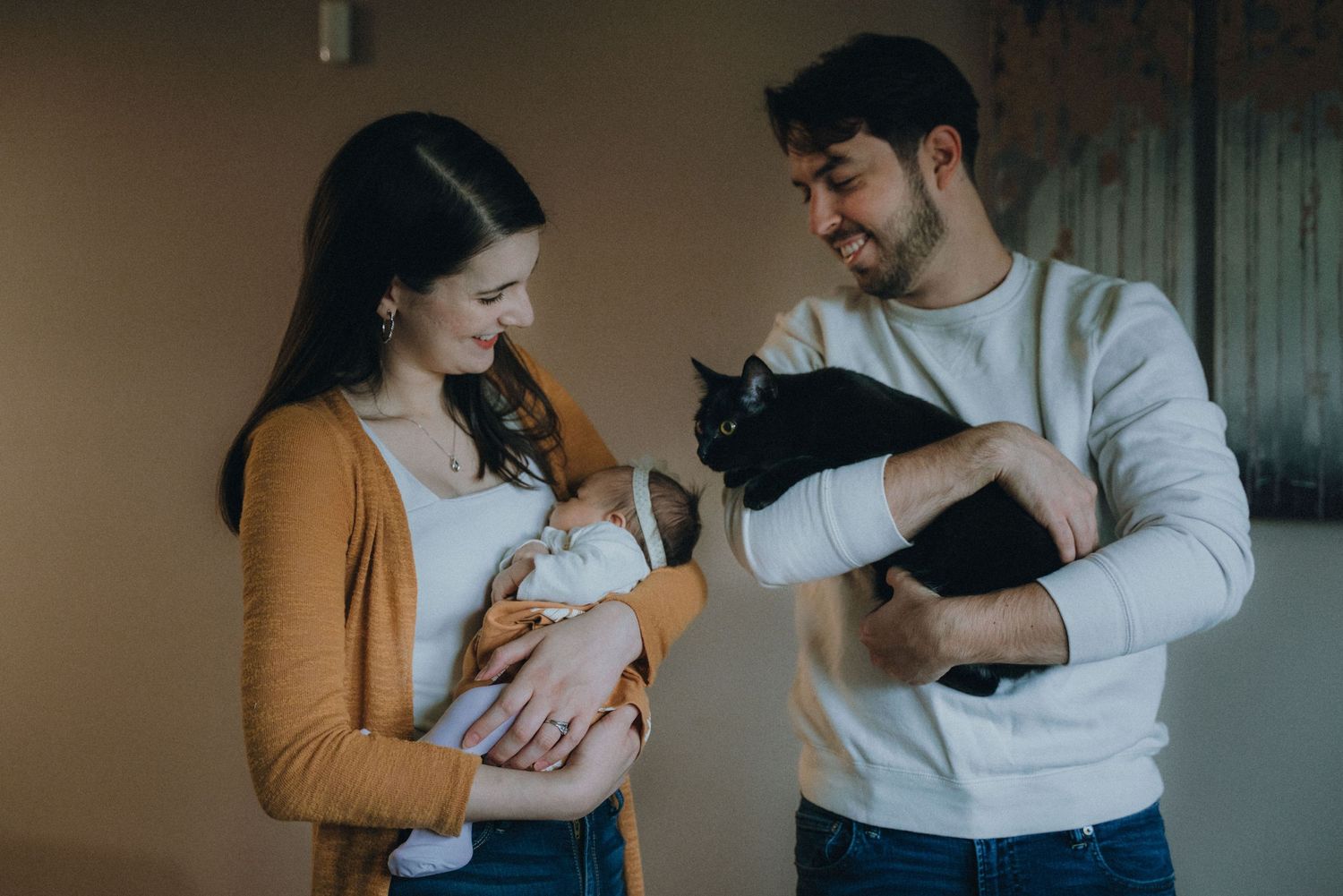 Parents in casual attire sharing sweet moment with their newborn at home.