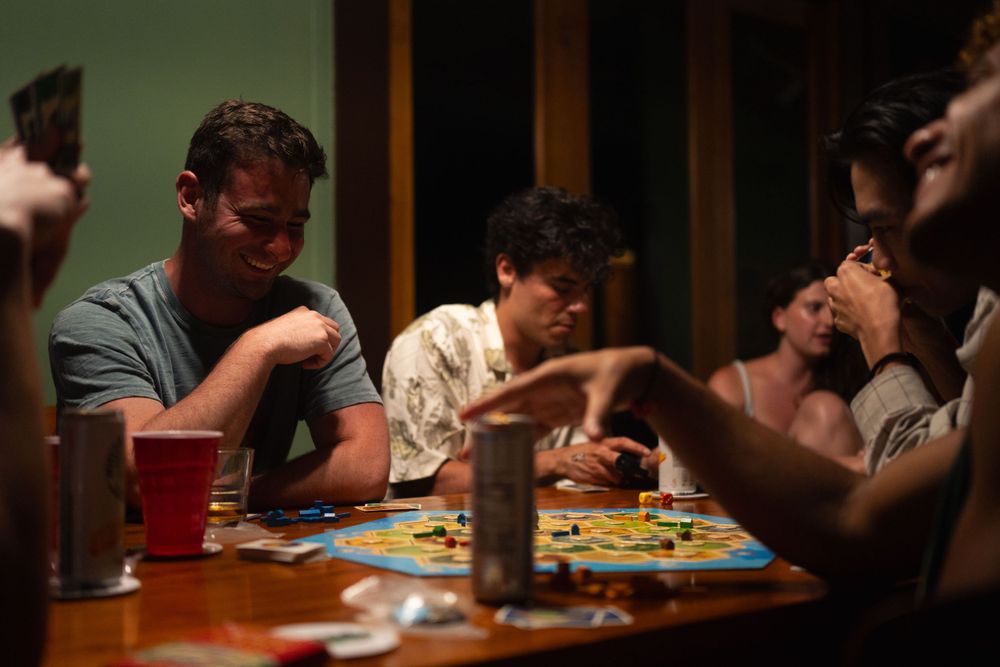 People engaged in a competitive board game session around a wooden table.