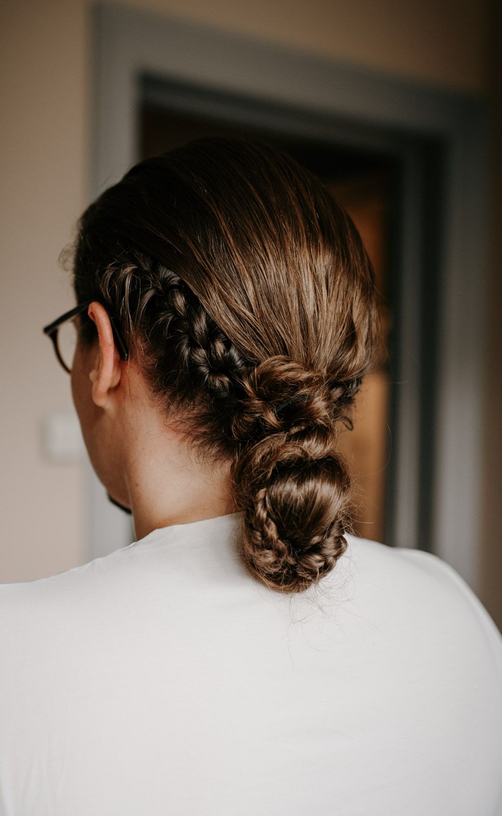 Back view of elegant braided updo hairstyle with Dutch braid leading into a low bun for a wedding.